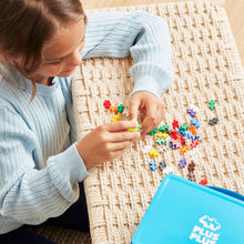 Load image into Gallery viewer, Child playing with colorful beads on a woven mat