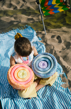 Load image into Gallery viewer, Child exploring open-ended play with Stapelstein® stones on the sandy beach.