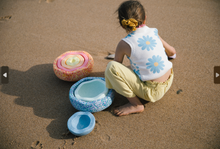 Load image into Gallery viewer, Child engaging in imaginative outdoor play with Stapelstein® stones by the sea.