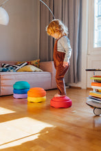 Load image into Gallery viewer, Brightly coloured Stapelstein® Rainbow Classic stones scattered across a playroom floor during free play.