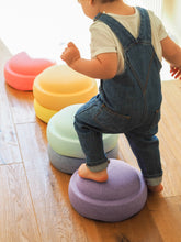 Load image into Gallery viewer, Child stepping on Stapelstein® Original Rainbow Pastel stones while playing an indoor balance game.