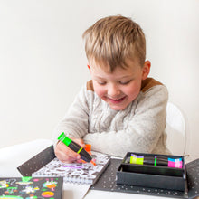 Load image into Gallery viewer, Tiger Tribe Neon Colouring Set – lifestyle shot of child colouring – the outdoor kid.
